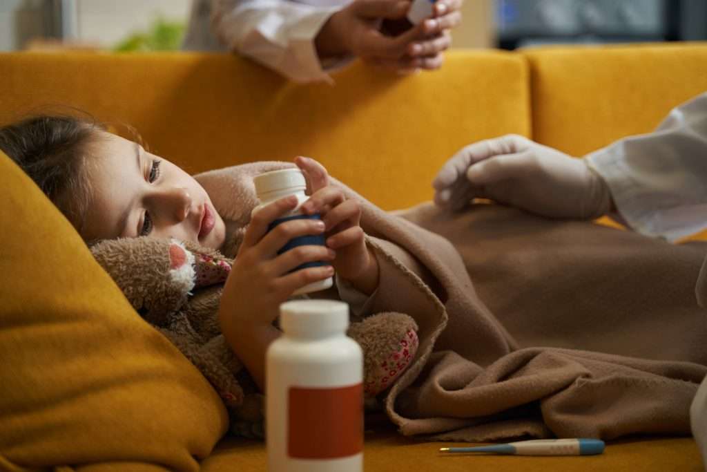 Child at home holding medication during a nurse-supervised medication administration visit