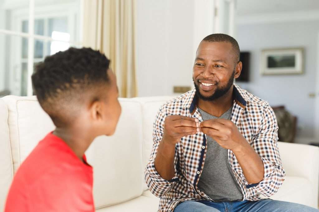 Father and son communicating on a couch at home, supported by respite care